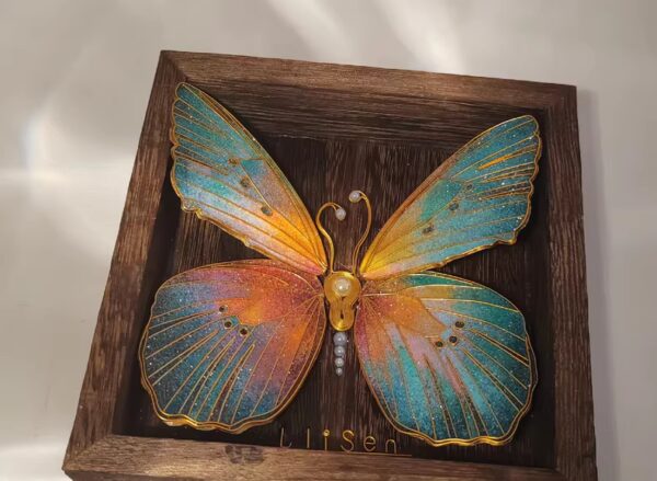 A butterfly forged of light and metal — golden hues at its core, silver-black at its edge.